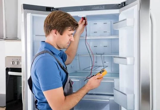 Technician using a meter to inspect refrigerator components